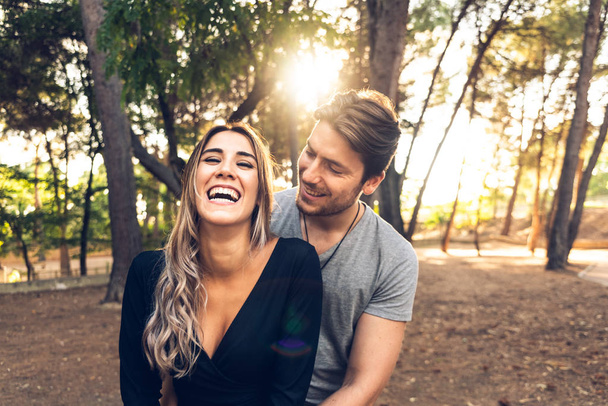 Ευτυχισμένο ζευγάρι στην αγάπη γέλιο μπροστά από την κάμερα σε ένα πάρκο w - Φωτογραφία, εικόνα