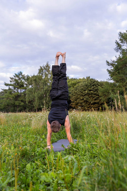 Homme inspiré faisant du yoga asanas dans le parc de la ville. Fitness extérieur et concept d'équilibre de vie. Sirsasana
 - Photo, image