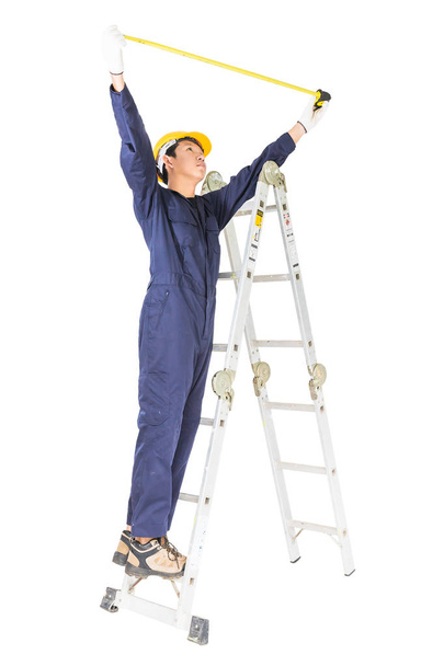 Handwerker in Uniform steht beim Maßband auf Leiter  - Foto, Bild