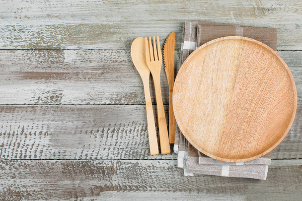 Vista dall'alto di piatti in legno e posate su sfondo tavolo in legno. Piatto vuoto. Concetto di cibo ridicolo. Copia spazio, luogo per l'oggetto
 - Foto, immagini