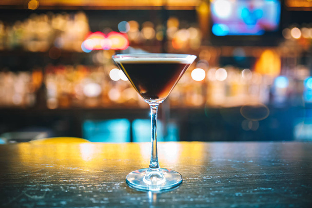 Кофейный коктейль с мартини и кофейными зёрнами на барной стойке с размытым фоном
 - Фото, изображение