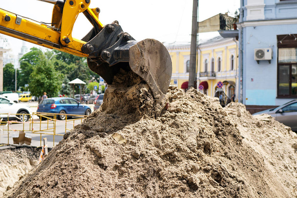 Taş ocağındaki yol şantiyesindeki inşaat makineleri toprak kazıyor ve kum döküyor. - Fotoğraf, Görsel