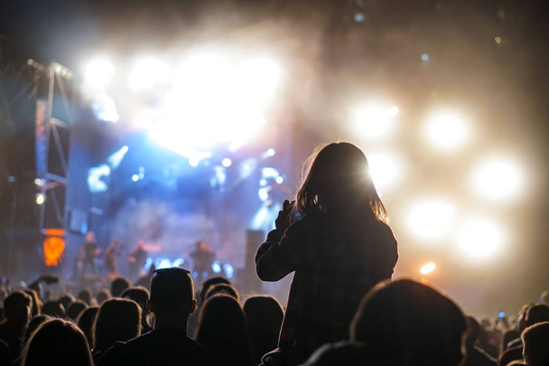 Дитина розважається на плечах своїх батьків, тримаючи з собою руки на концерті на відкритому рок-музиці
 - Фото, зображення
