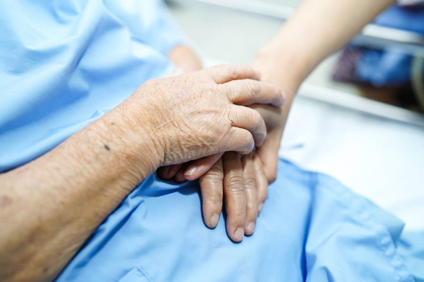 Tocar las manos Asiática anciana o anciana anciana paciente con amor, cuidado, ayuda, aliento y empatía en enfermería sala de hospital: concepto médico fuerte saludable
 - Foto, imagen