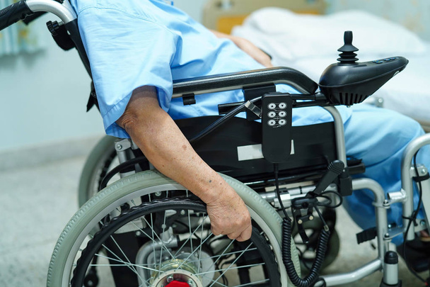 Aasialainen vanhempi tai iäkäs vanha nainen nainen potilas sähköpyörätuolissa kaukosäätimellä hoitotyön sairaalassa: terve vahva lääketieteellinen käsite
 - Valokuva, kuva