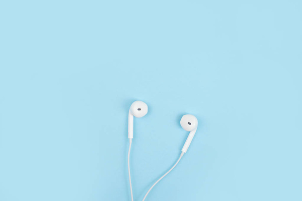 Earphone on a blue background. Close up. - Foto, afbeelding