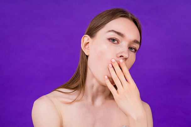 sleepy young teen girl yawns on purple background in studio - Foto, imagen