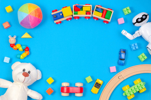Kids toys background. White teddy bear, wooden train, toy car, robot, colorful blocks on light blue background - Photo, Image