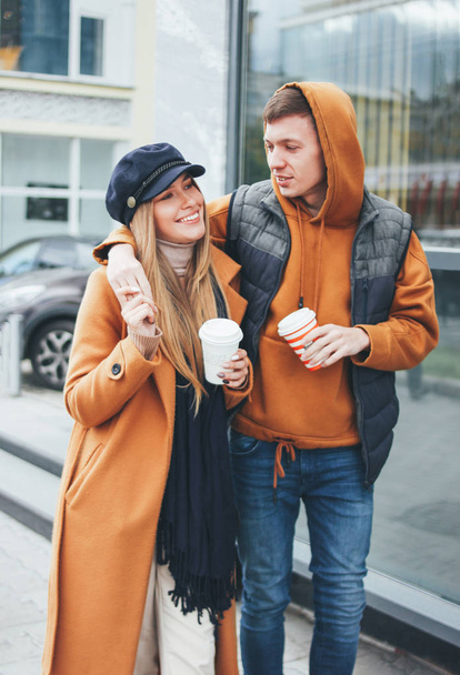 Happy young couple in love teenagers friends dressed in casual style walking together on city street in cold season - Fotó, kép