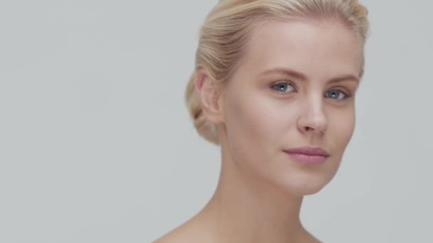 Studio portrait of young, beautiful and natural blond woman applying skin care cream. Face lifting, cosmetics and make-up. - Filmagem, Vídeo