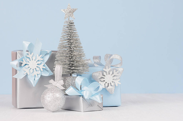Graceful home decor for christmas celebration - pastel blue and metallic gift boxes with silver christmas tree, shiny ball on white wood board, copy space. - Foto, Imagen