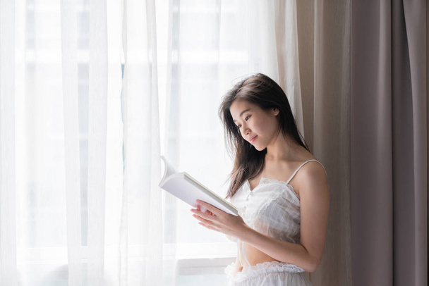 Asian women while reading book near window with shear curtain /  - Foto, immagini