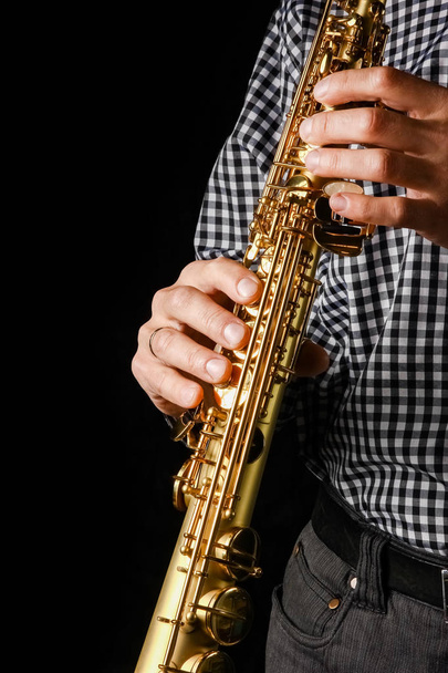 soprano saxophone in hands on a black background - Foto, imagen