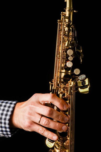 soprano saxophone in hands on a black background - Foto, afbeelding