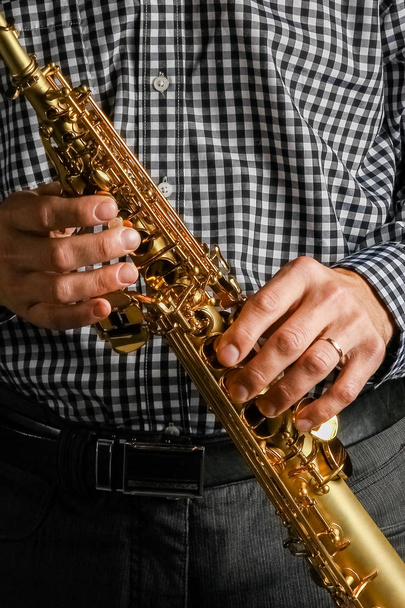 soprano saxophone in hands on a black background - Фото, зображення