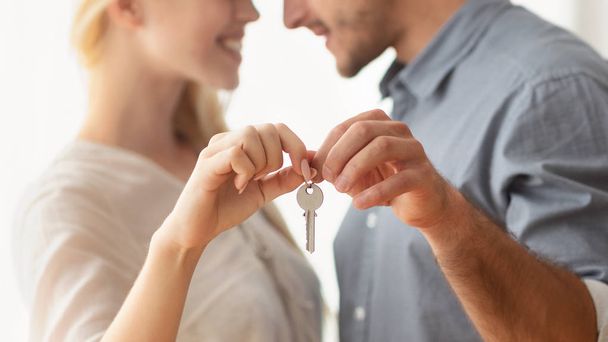 Неузнаваемые мужчина и женщина обнимаются с новым ключом от дома в помещении
 - Фото, изображение