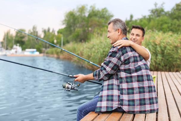 Genç adam ve babası nehirde balık tutuyor. - Fotoğraf, Görsel