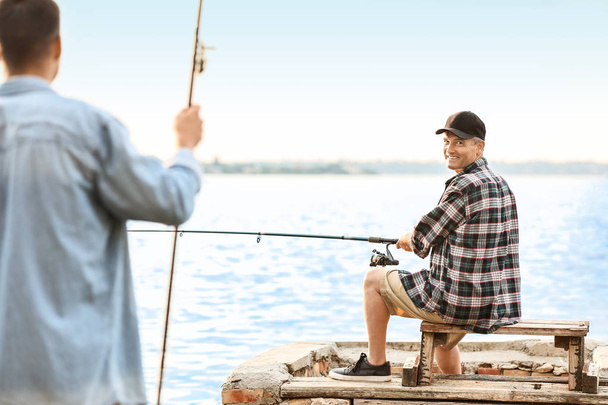 Giovane uomo e suo padre pesca sul fiume
 - Foto, immagini