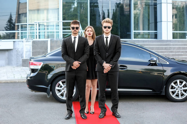 Famosa celebridade com guarda-costas perto do carro ao ar livre
 - Foto, Imagem