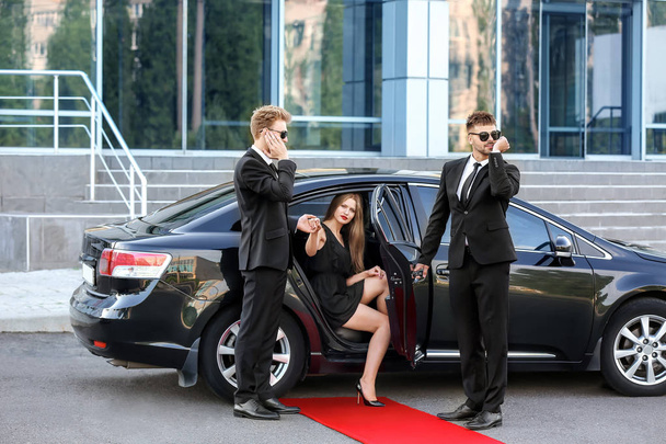 Guarda-costas ajudando jovem celebridade a sair do carro
 - Foto, Imagem