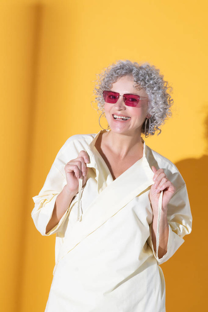 Curly woman wearing pink glasses smiling broadly - Foto, imagen