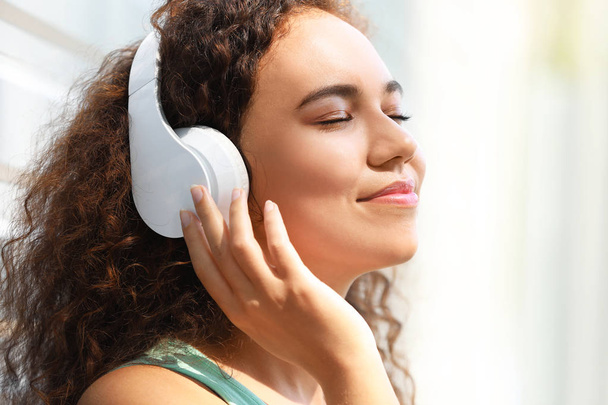 Kaunis afroamerikkalainen nainen kuuntelee musiikkia ulkona
 - Valokuva, kuva