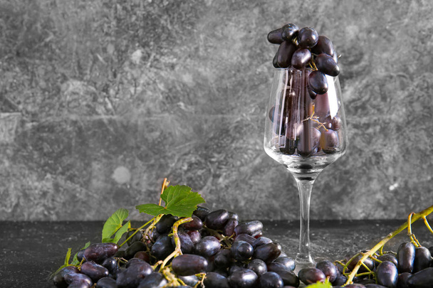 Słodkie winogrona ze szkłem winnym na szarym tle - Zdjęcie, obraz