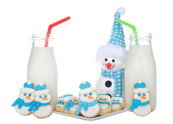 Schneemänner Zuckerkekse mit blauen Tüchern und flauschigen blau-weißen Hüten auf einem Teller mit Milchflaschen mit grünen und roten Strohhalmen. mehr Schneemannkekse neben Milchgläsern - Foto, Bild