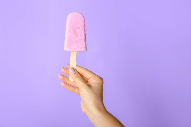 Mano femenina con sabroso helado de arándanos sobre fondo de color
 - Foto, imagen