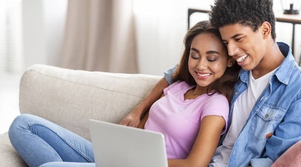 Smiling african teen couple relaxing and watching movie on laptop - Фото, зображення
