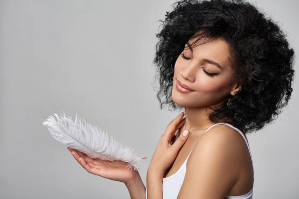 Beautiful mixed race woman holding white ostrich feather - Zdjęcie, obraz