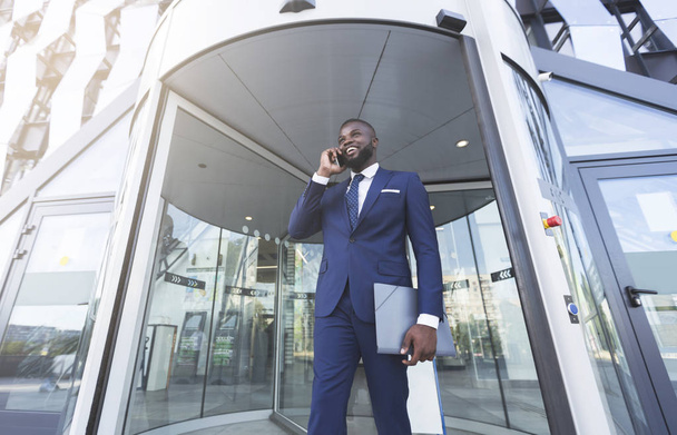 Afro Liikemies puhuu matkapuhelin vastaan sisäänkäynti Office Building
 - Valokuva, kuva