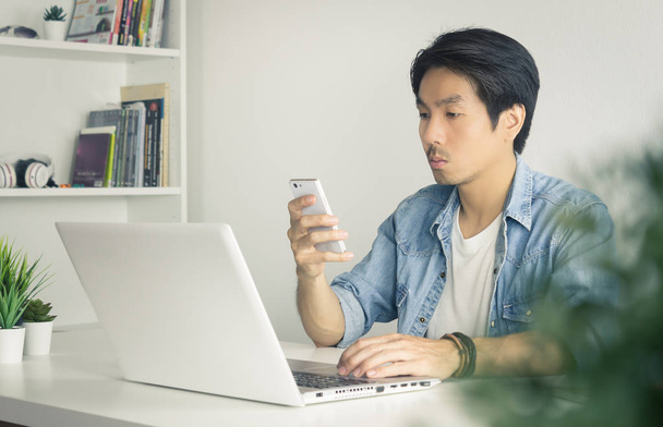 Портрет Азиатский случайный бизнесмен Проверка почты и чата с коллегой по смартфону в винтажном тоне
 - Фото, изображение