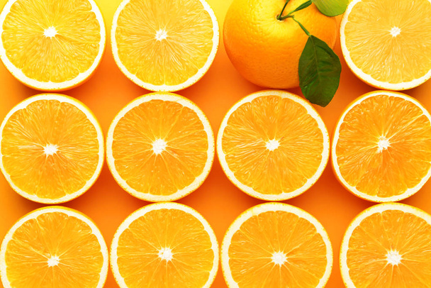 Whole orange among cut ones on color background. Concept of uniqueness - 写真・画像
