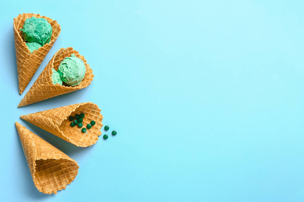 Tasty spirulina ice-cream and waffle cones on color background - 写真・画像