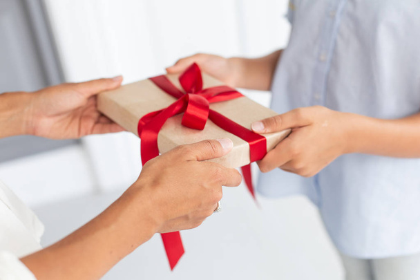 Closeup of thin gift box in hands of mother and daughter. Selective focus - Photo, image