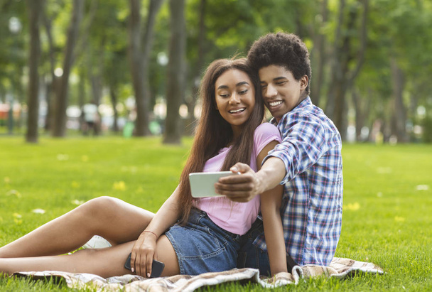 Romantic teenagers taking selfie on a date in park - Foto, imagen