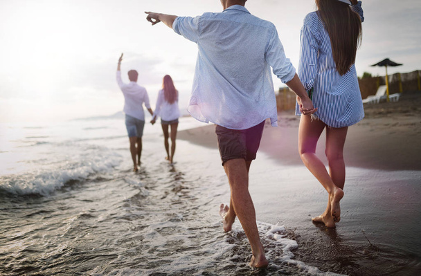 Friends having fun on the beach under sunset sunlight. - Фото, изображение