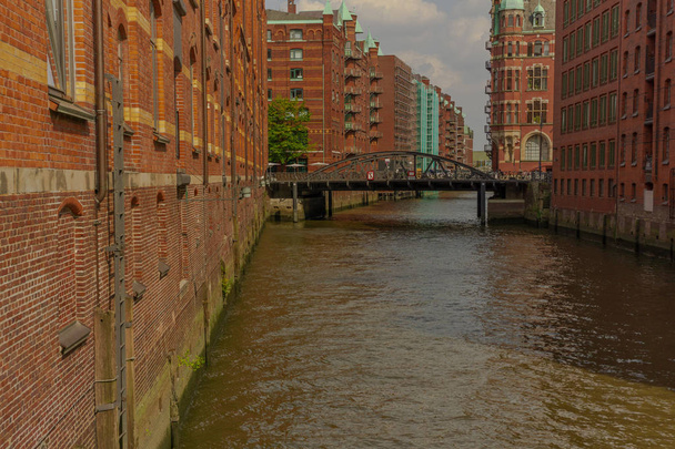 a river through hamburg with big red houses and in the background a bridge - Photo, Image