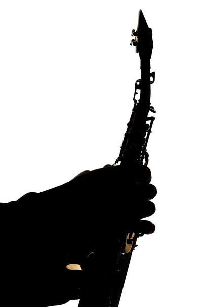 saxafon em um fundo branco nas mãos de uma silhueta músico
 - Foto, Imagem