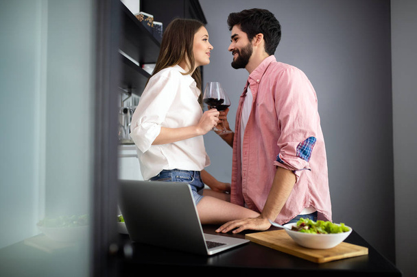 Image of happy young couple with glasses of red wine eating salad - Foto, afbeelding