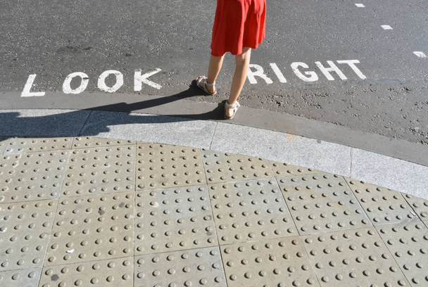 Peatonal de pie junto a la típica señal de cruce de carreteras en Londres
 - Foto, Imagen