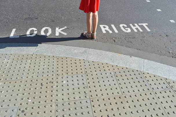 Pedestrian standing next to typical road crossing sign in London - 写真・画像