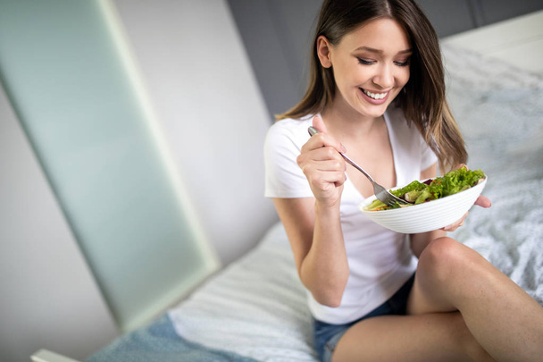 Woman eating healthy salad after working out at home - Фото, изображение