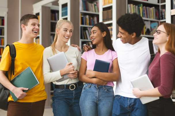 Estudantes internacionais alegres conversando na biblioteca da faculdade
 - Foto, Imagem