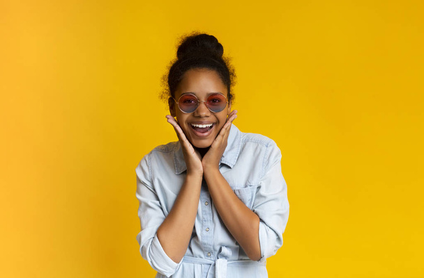 Roztomilé teen dívka v slunečních brýlích s úsměvem a pózování na kameru - Fotografie, Obrázek