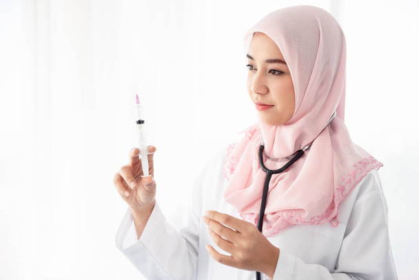 Muslim woman doctor holding a syringe. - Zdjęcie, obraz