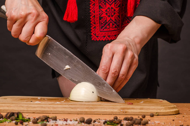 Mano de niña con un cuchillo cortando cebollas sobre tabla de madera
 - Foto, Imagen