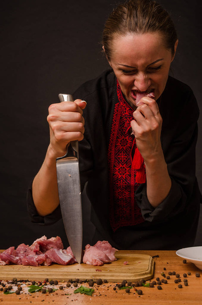 Une femme tient un gros steak dans sa fourchette et lui lèche les lèvres
. - Photo, image