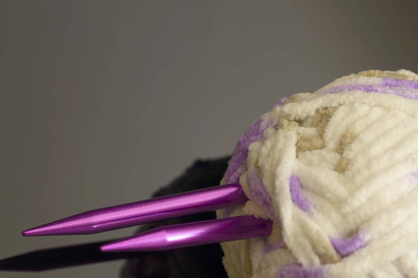 concepto de artesanía y costura - primer plano de agujas y bolas de punto de hilo con bufanda sin terminar
 - Foto, imagen